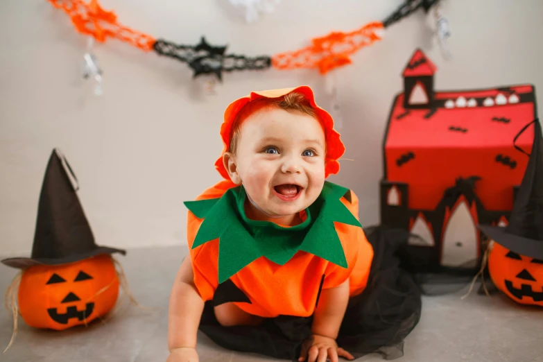 a baby in a halloween costume sitting on the floor, by Julia Pishtar, shutterstock, happily smiling at the camera, instagram post, delightful surroundings, very orange