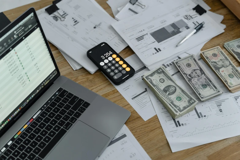 a laptop computer sitting on top of a wooden desk, piles of money, numerical, thumbnail, wetastudiofx