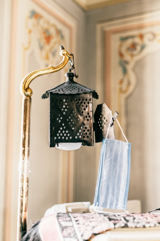 a lamp that is on top of a table, an album cover, inspired by Quirizio di Giovanni da Murano, unsplash, art nouveau, facemask, hearst castle, laundry hanging, carbide lamp