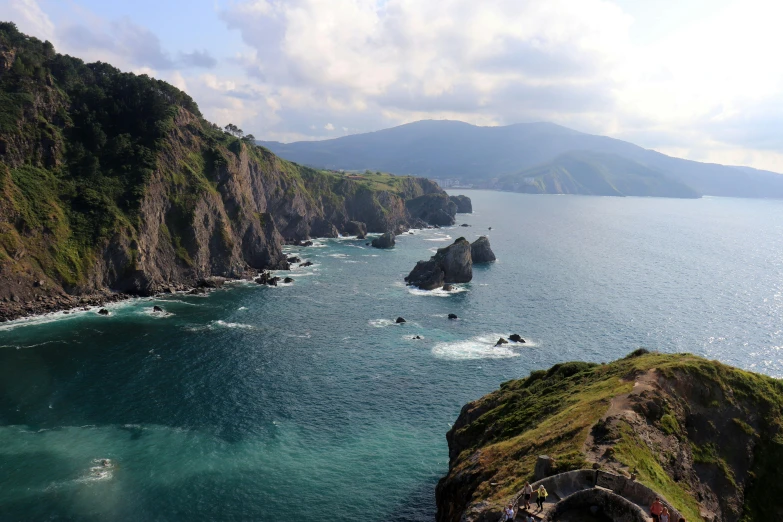 a large body of water next to a lush green hillside, by Muggur, pexels contest winner, renaissance, coastal cliffs, ehime, conde nast traveler photo, profile image