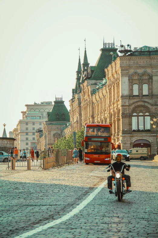 a man riding a motorcycle down a cobblestone street, pexels contest winner, socialist realism, red square moscow, vw bus on a street, 🚿🗝📝, wide greenways