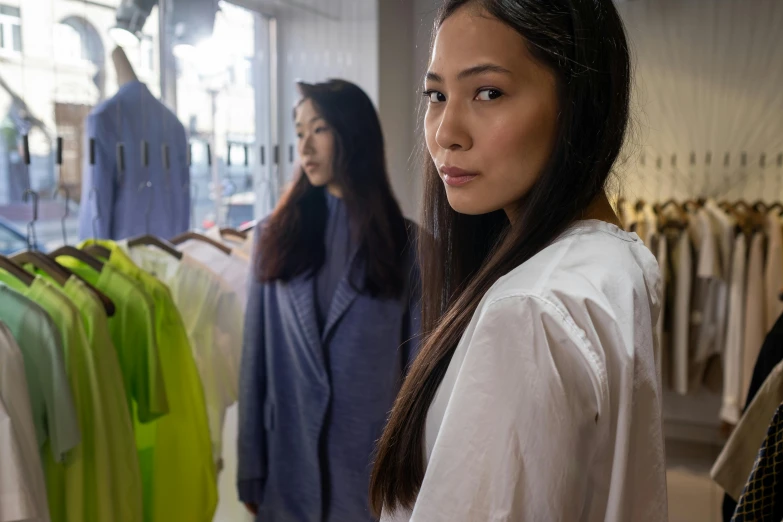 a woman standing in front of a rack of clothes, inspired by Kim Tschang Yeul, pexels contest winner, hyperrealism, wearing hi vis clothing, two models in the frame, wearing a linen shirt, candid