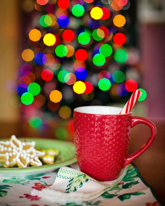 a red mug sitting on top of a table next to a plate of cookies, pexels, happening, christmas lights, square, colorful image, multiple stories