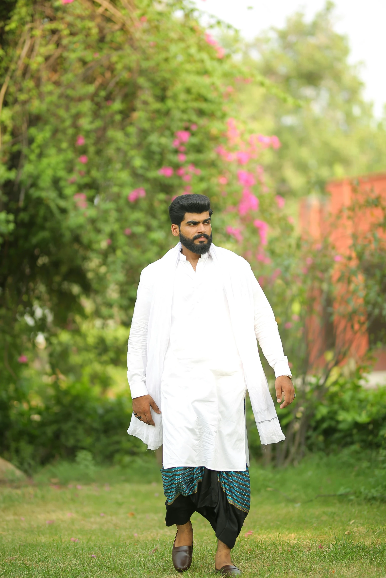 a man walking across a lush green field, an album cover, by Riza Abbasi, pexels contest winner, wearing a labcoat, casual pose, desi, in garden