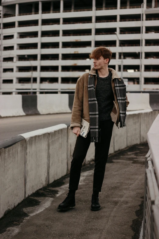 a man standing on top of a bridge next to a tall building, by Carey Morris, trending on pexels, renaissance, wearing a turtleneck and jacket, male ulzzang, hr ginger, standing in a parking lot