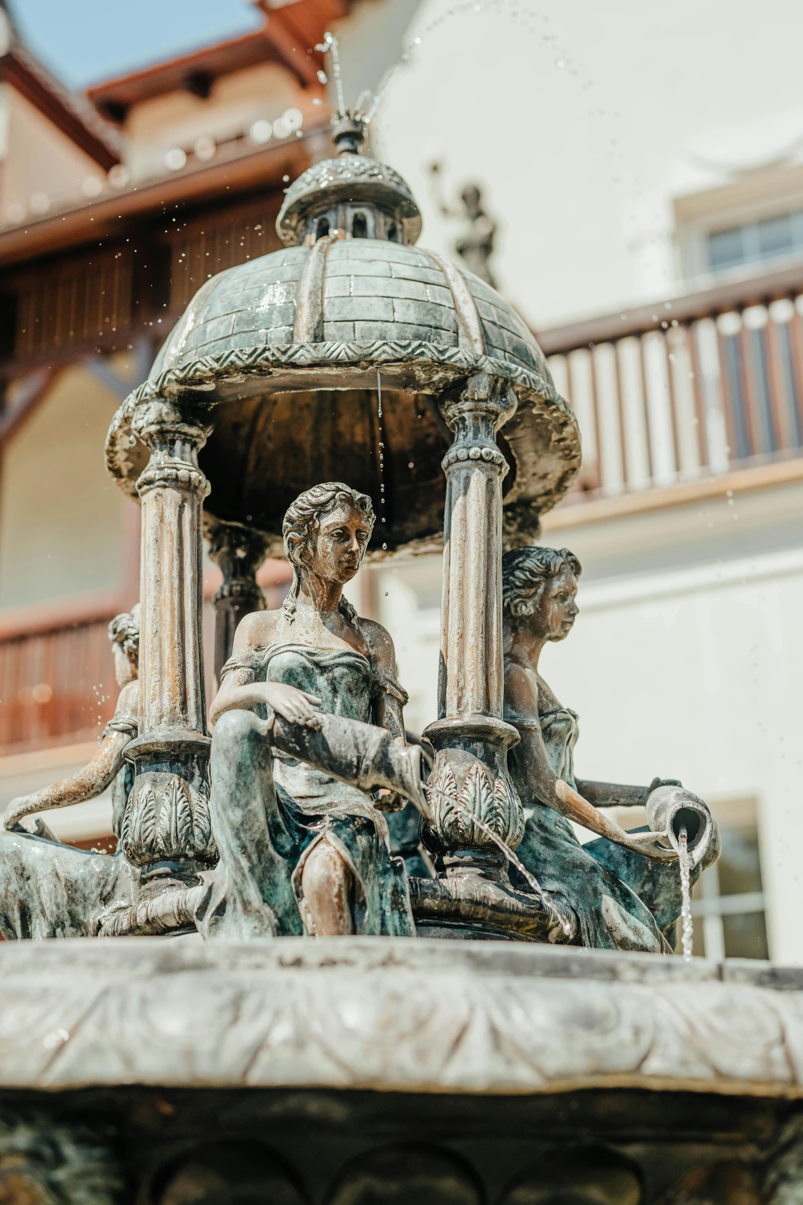 a close up of a fountain with a building in the background, a statue, ornate furniture, village square, intricate copper details, 3 nymphs circling a fountain