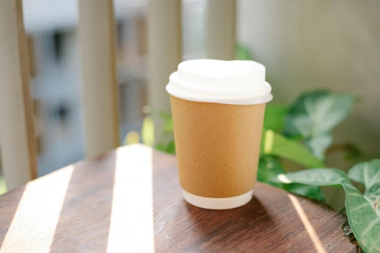 a coffee cup sitting on top of a wooden table, profile image, in the sun, detailed product image, on a white table