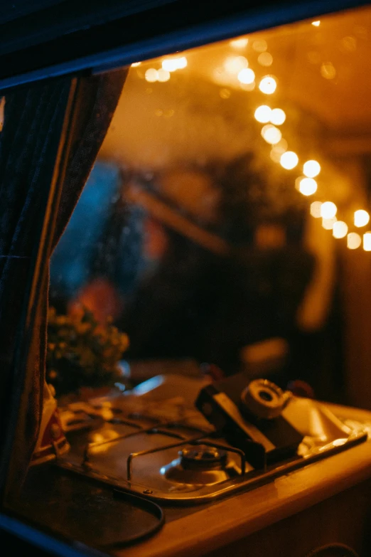 a camera sitting on top of a table next to a window, by Elsa Bleda, unsplash contest winner, romanticism, string lights, interior of a tent, festive atmosphere, dramatic lighting; 4k 8k