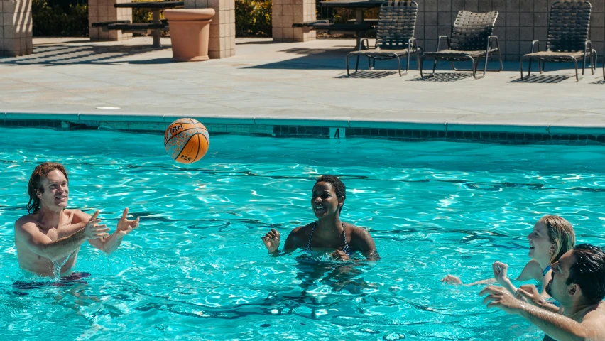 a group of people playing with a ball in a pool