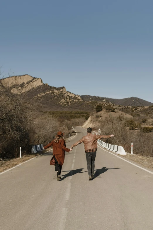 two people walking down a road holding hands, an album cover, unsplash, renaissance, hollister ranch, hills, awkward, wes anderson style