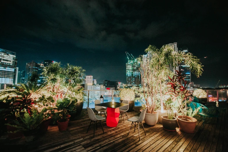a table and chairs on top of a wooden deck, by Austin English, unsplash contest winner, lush tress made of city lights, kuala lumpur, terrarium lounge area, rooftop party