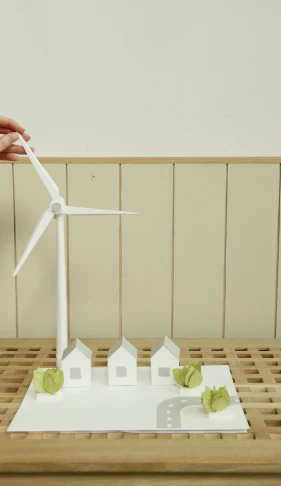 a person holding a paper model of a wind turbine, by Paul Bird, conceptual art, tabletop model buildings, white houses, thumbnail, ecovillage