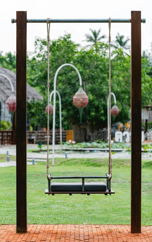 a wooden swing set sitting on top of a lush green field, terrarium lounge area, thawan duchanee, shot with sony alpha, round-cropped