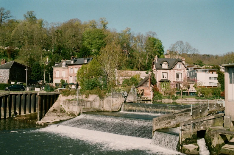 a river running through a lush green forest filled with trees, an album cover, unsplash, les nabis, french village exterior, pink, medium format film photography, fishing town