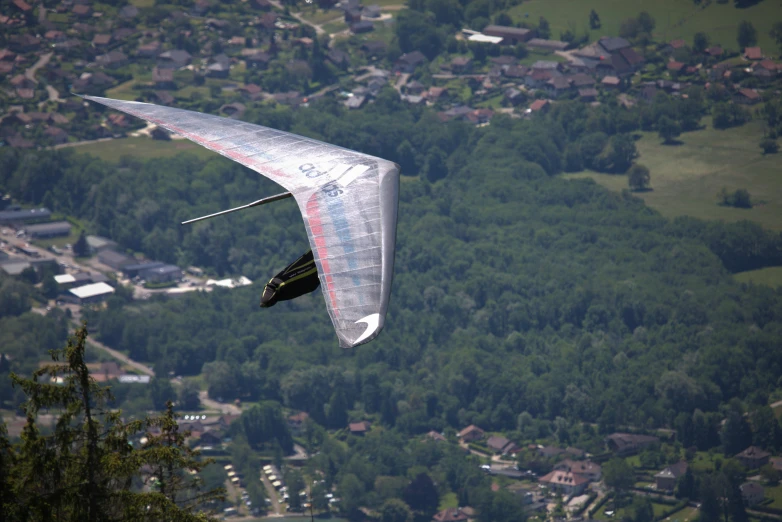 a man flying a kite over a lush green hillside, by Bernard Meninsky, pexels contest winner, figuration libre, flying car, massive vertical grand prix race, silver wings, seen from the side
