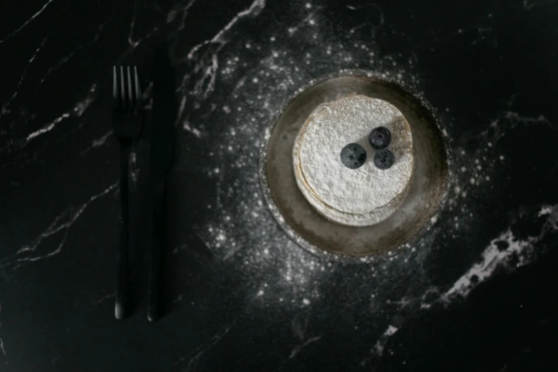 a close up of a plate of food with a fork and knife, a portrait, inspired by Pierre Pellegrini, trending on unsplash, purism, manta ray made of pancake, made of liquid metal and marble, space dust, black marble