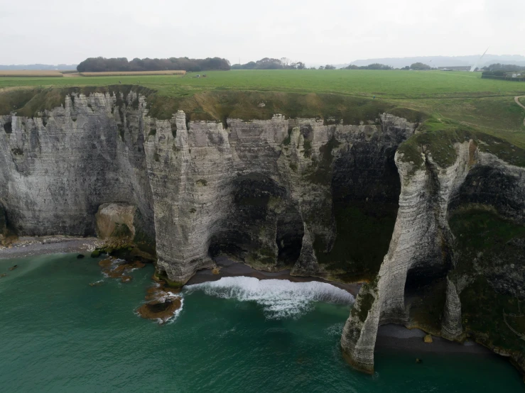 a large body of water next to a cliff, by Raphaël Collin, pexels contest winner, les nabis, the normandy landings, white stone arches, 8 k movie still, a hyper realistic