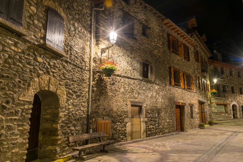 a stone building with a bench in front of it, pexels contest winner, romanesque, nightime village background, spanish, gray, thumbnail