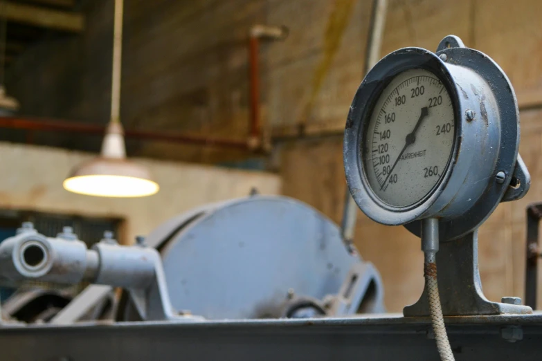 a gauge sitting on top of a piece of metal, unsplash, process art, in an underground laboratory, blue - grey gear, working in the forge, promo image