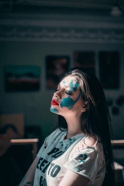 a woman with face paint in a dark room, an airbrush painting, inspired by Elsa Bleda, trending on pexels, aestheticism, on a bright day, sleepy expression, blue paint on top, center of image