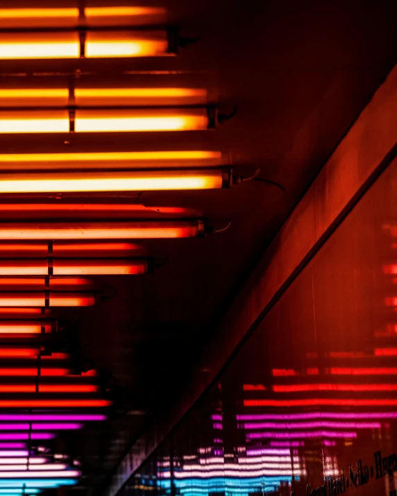 a group of neon lights hanging from the ceiling of a building, by Carey Morris, pexels contest winner, orange neon stripes, red light saber, barely lit warm violet red light, red and blue black light