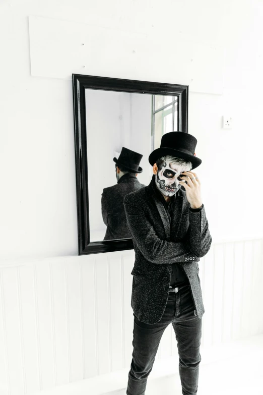 a man in a suit and top hat standing in front of a mirror, inspired by James Bolivar Manson, pexels contest winner, skull face paint, with a white background, full body photo, instagram photo