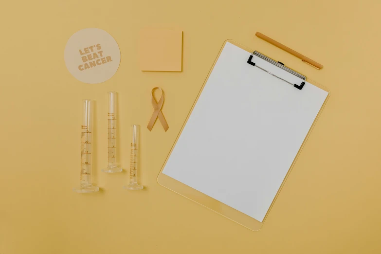 a clipboard sitting on top of a table next to a pair of scissors, healing tubes, yellow hue, white ribbon, minimalistic aesthetics