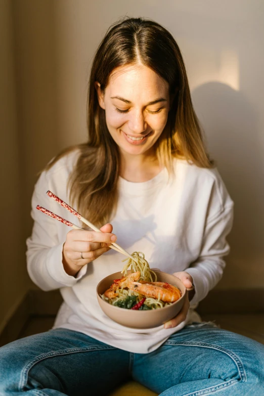 a woman sitting on the floor eating a bowl of food, inspired by Nishida Shun'ei, pexels contest winner, happy chef, middle length hair, warm friendly face, brooke ashling