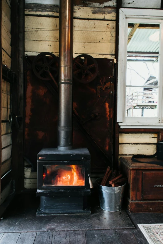 a wood burning stove in the corner of a room, by Jessie Algie, unsplash, al fresco, steam engine, lachlan bailey, winter