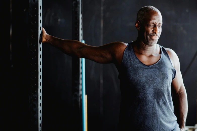 a man holding a barbell in a gym, a portrait, pexels contest winner, lance reddick, old male, background image, lachlan bailey