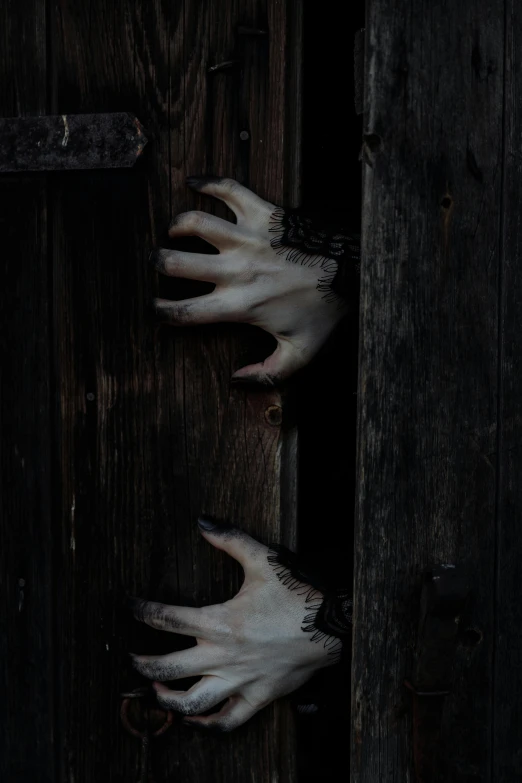 a pair of hands sticking out of a wooden door, an album cover, by Elsa Bleda, unsplash, symbolism, very sharp vampire fangs teeth, white horns, dark. no text, carved