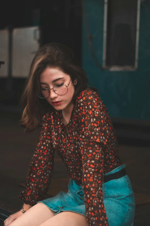 a woman sitting on the ground using a laptop, a picture, inspired by Elsa Bleda, trending on pexels, modernism, square rimmed glasses, portrait soft low light, patterned, girl standing