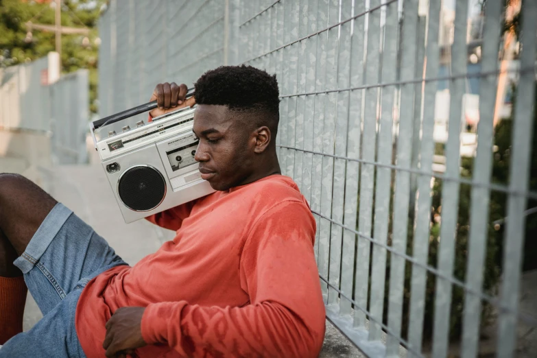 a man sitting on the ground with a boombox on his head, trending on pexels, man is with black skin, young man with short, teenage girl, thumbnail