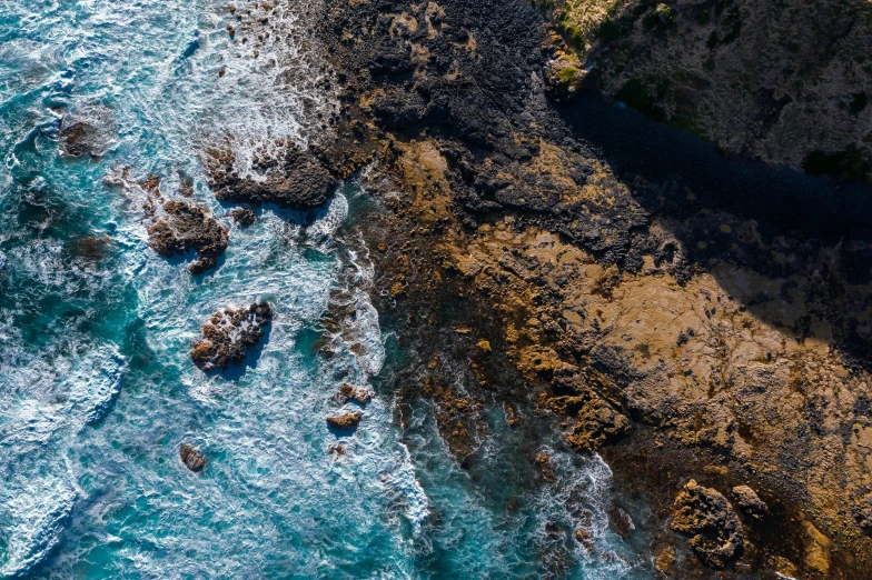 a large body of water next to a cliff, pexels contest winner, process art, close-up from above, rocky coast, te pae, top down photo at 45 degrees