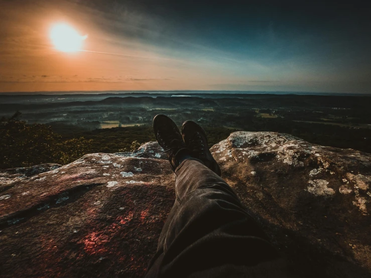a person sitting on top of a large rock, pexels contest winner, high soles, end of day, reclining, view