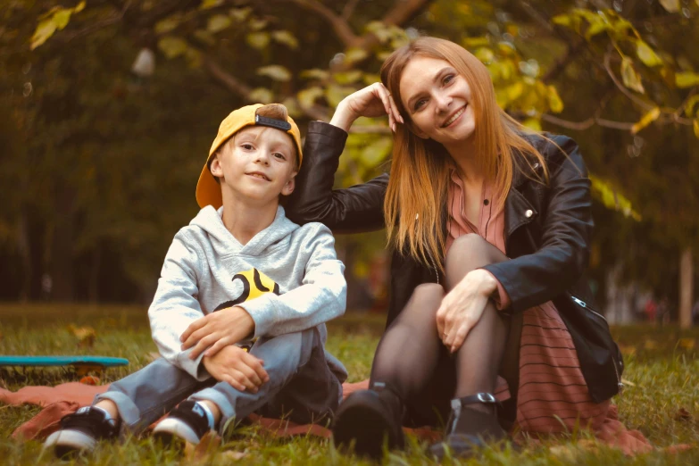 a woman sitting next to a boy on a blanket, a portrait, pexels, realism, red haired teen boy, 15081959 21121991 01012000 4k, a blond, in a park