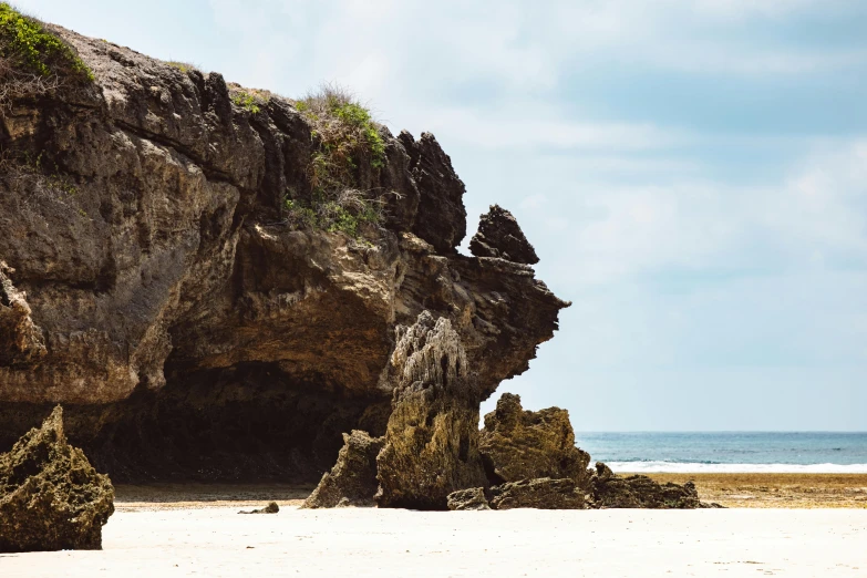 a man riding a surfboard on top of a sandy beach, unsplash, minimalism, overgrown stone cave, indonesia, australian beach, highly detailed rock structures