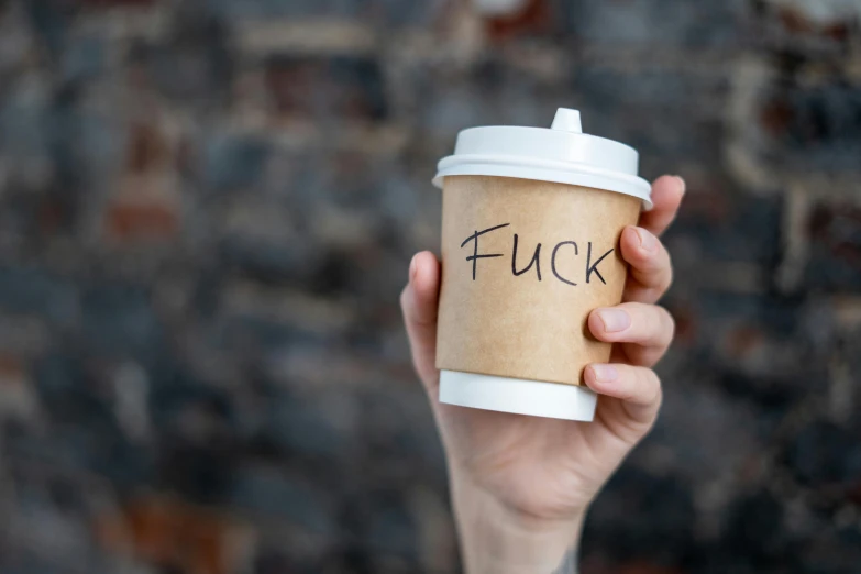 a person holding a coffee cup with the word fuck written on it, an album cover, by Tracey Emin, unsplash, graffiti, annoyed expression, coffee cups, very buff, 555400831