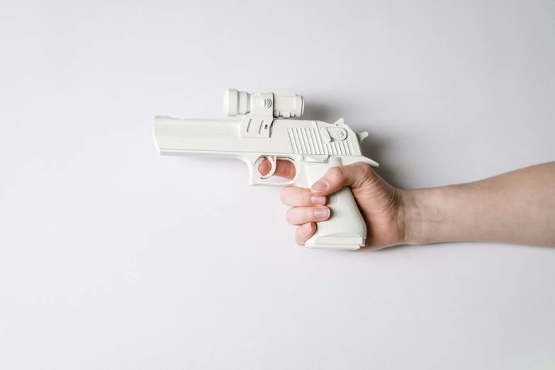 a person holding a toy gun in their hand, inspired by Carl Gustaf Pilo, unsplash, photorealism, white body, ultra mega super hyper realistic, air shot, on a pale background