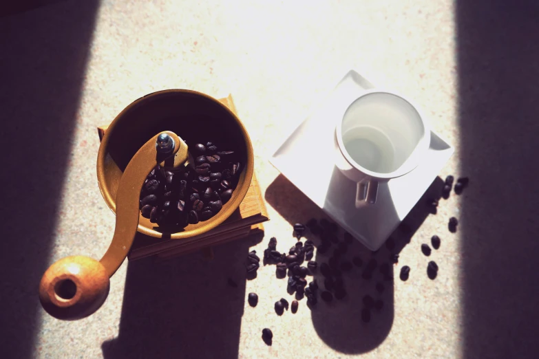 a coffee grinder sitting next to a cup of coffee, by Romain brook, summer sunlight, instagram picture, beans, blender