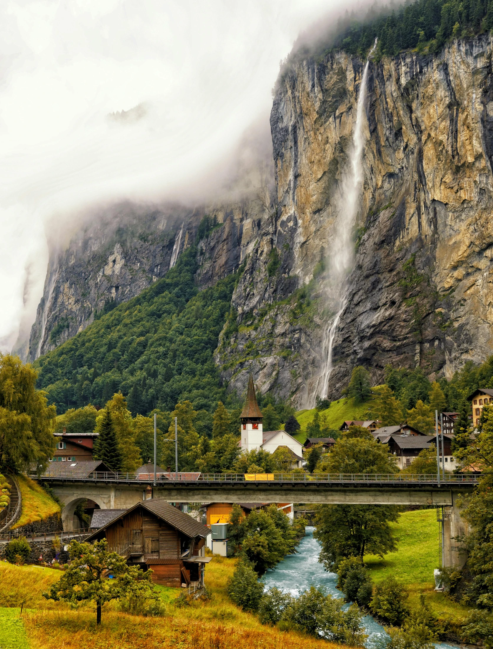 a river running through a lush green valley, by Karl Stauffer-Bern, pexels contest winner, renaissance, tall stone spires, waterfall backdrop, quaint village, today\'s featured photograph 4k