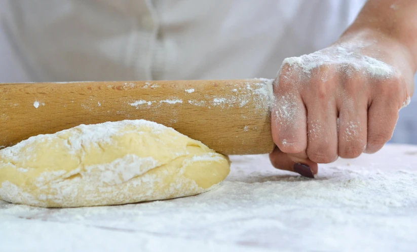 a person rolling dough on a table with a rolling pin, inspired by Richmond Barthé, trending on pexels, panoramic, fan favorite, holding a thick staff, silver，ivory