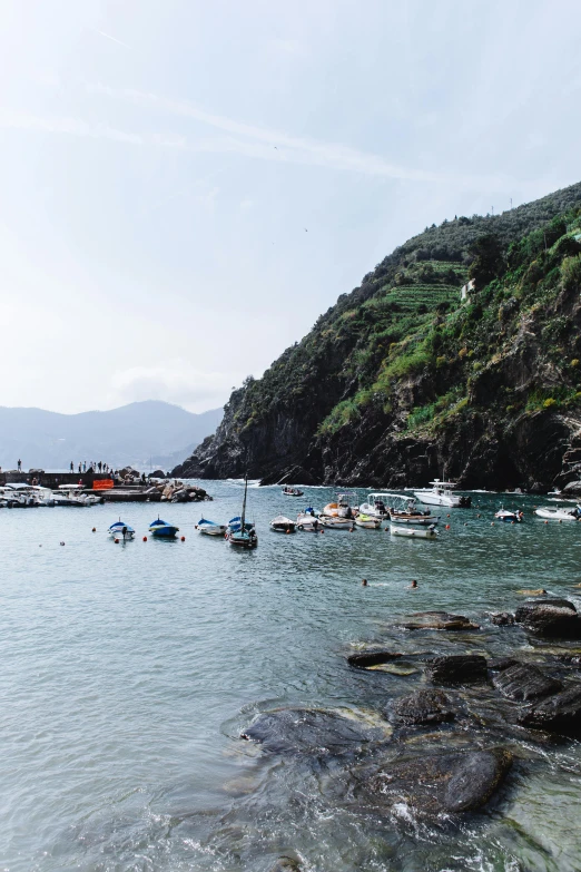 a group of boats floating on top of a body of water, a picture, by Carlo Martini, cinq terre, grotto, near a jetty, portra