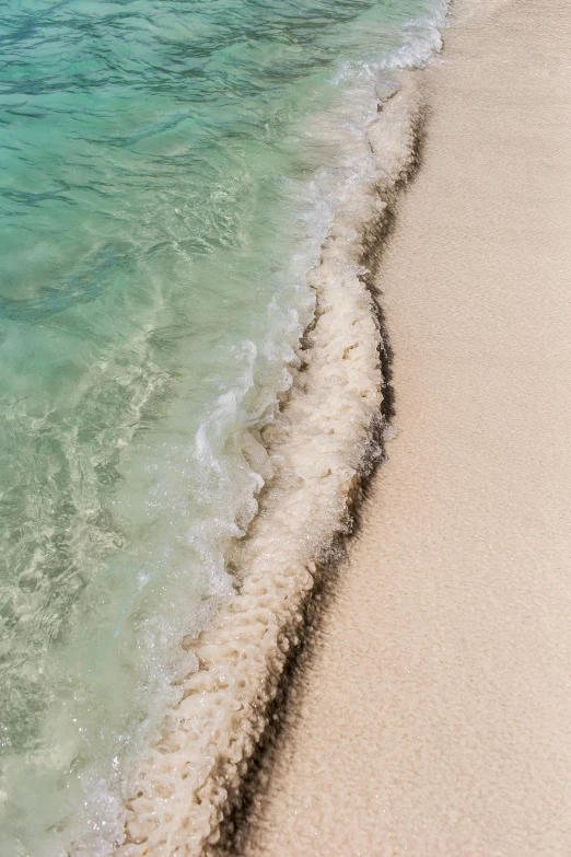 a large body of water next to a sandy beach, by Carey Morris, trending on unsplash, delicate coral sea bottom, somalia, high angle close up shot, wave breaking