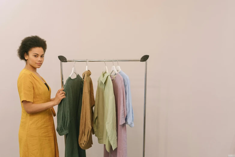 a woman standing in front of a rack of clothes, earthy colours, inspect in inventory image, tessa thompson inspired, ready to model