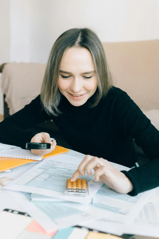 a woman sitting at a table with a calculator, pexels contest winner, avatar image, low quality photo, promo image, 1614572159