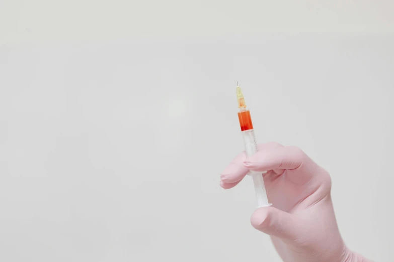 a close up of a person's hand holding a syll, unsplash, process art, syringe, white and orange, background image, full body image