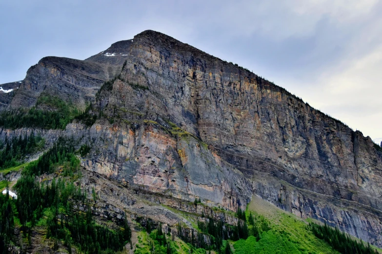 a mountain that has some trees on it, by Doug Wildey, pexels contest winner, high cliff, exterior photo, avatar image, structural geology