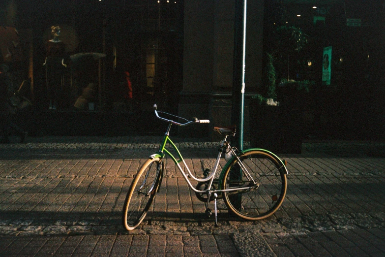 a bicycle parked on the side of a street, inspired by Elsa Bleda, pexels contest winner, green glow, in a square, fujicolor sample, high contrast of light and dark