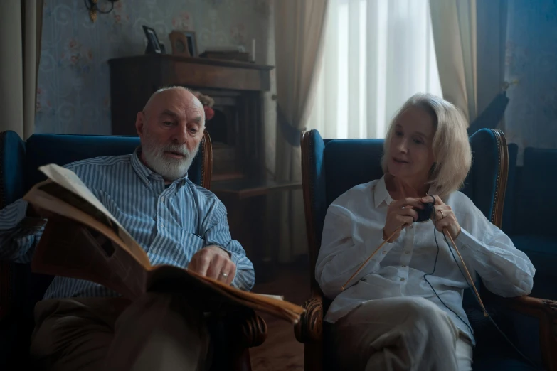 a man and a woman sitting in a chair, pexels contest winner, photorealism, parents watching, still from the film, reading, cinematic atmospheric photo